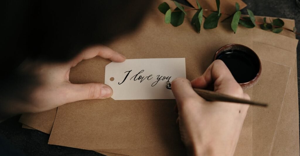 Person crafting a beautiful 'I love you' card with calligraphy, featuring eucalyptus and ink.