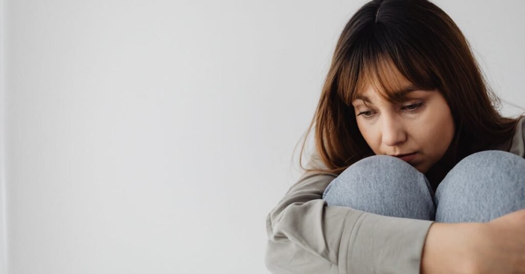 Caucasian woman sitting pensively indoors, capturing a moment of reflection and emotion.