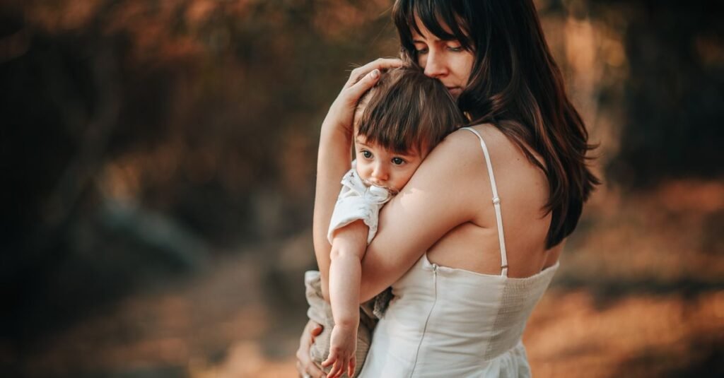 A tender moment of a mother holding her child outdoors in autumn.